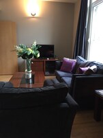 Una sala de estar moderna con un sofá, una mesa de centro, un televisor y un jarrón con flores.