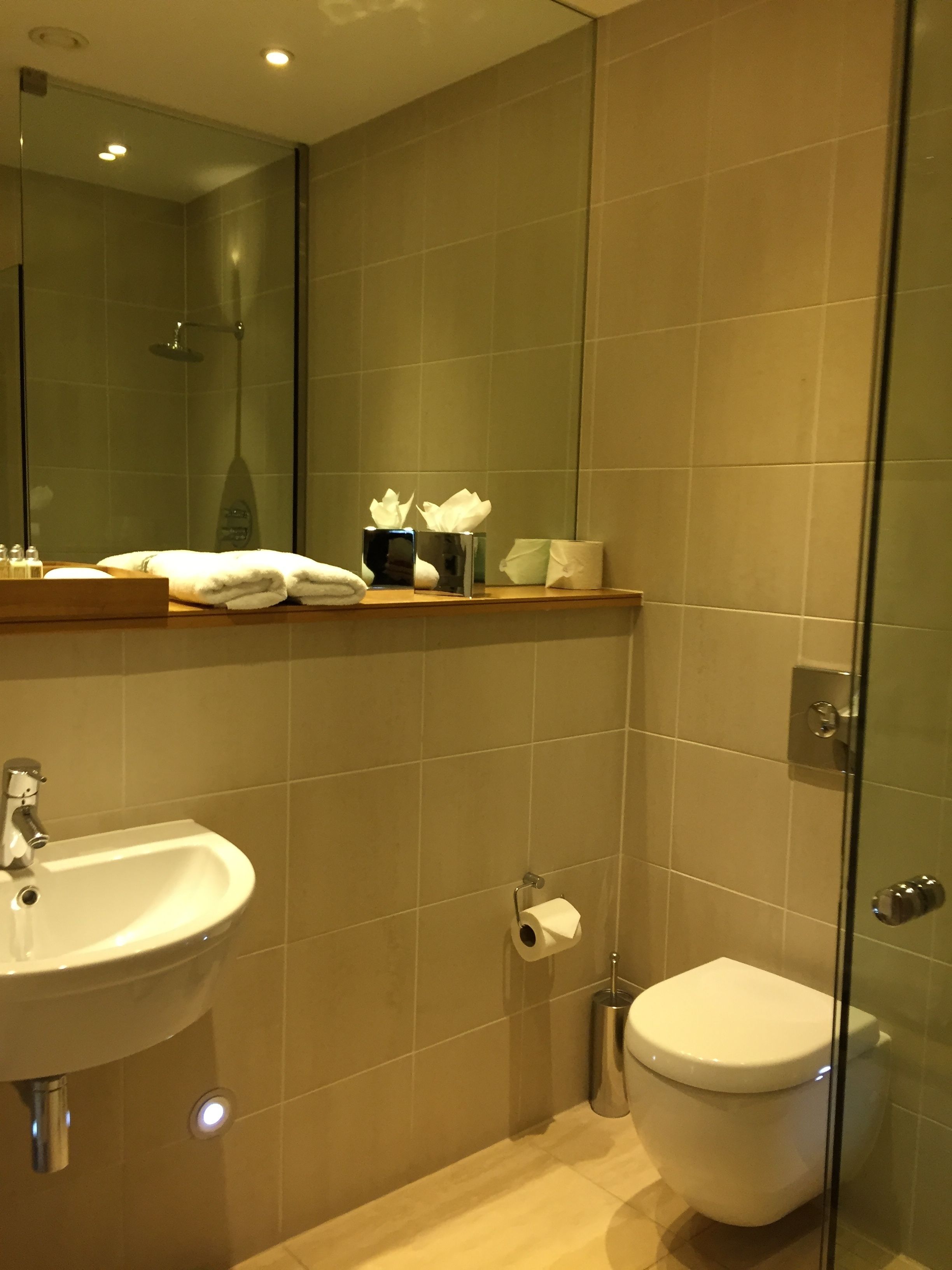 Un baño moderno con cabina de ducha de vidrio, lavamanos, inodoro y espejo.