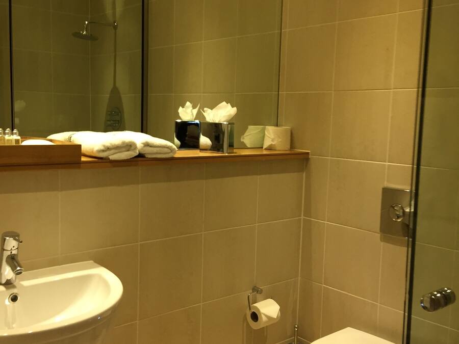 Un baño moderno con cabina de ducha de vidrio, lavamanos, inodoro y espejo.