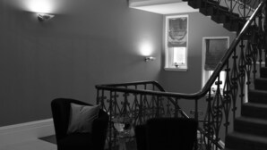 Ein schwarz-weißes Interieur mit einer Wendeltreppe, zwei schwarzen Sesseln und einem kleinen Tisch mit einer Vase.