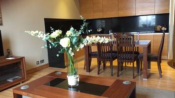 Una sala de estar moderna con una mesa de centro de madera, un florero con flores y un comedor con sillas y una mesa de madera.