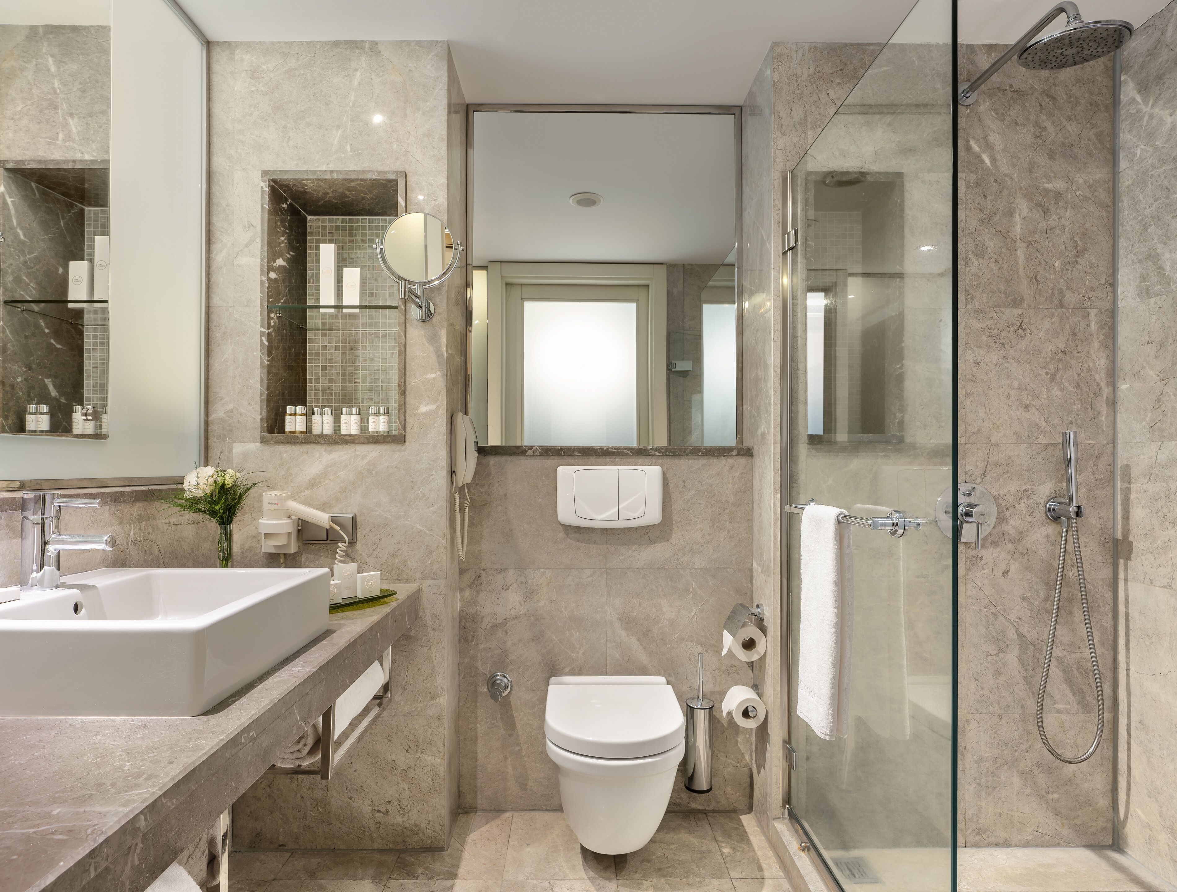 A modern bathroom with a glass-enclosed shower, a large sink, and a toilet.