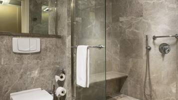 A modern bathroom with a glass-enclosed shower, a toilet, and a sink.