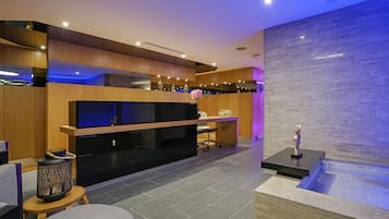 A modern interior with a wooden reception desk, a flat-screen TV, and a seating area with a round table and chairs.