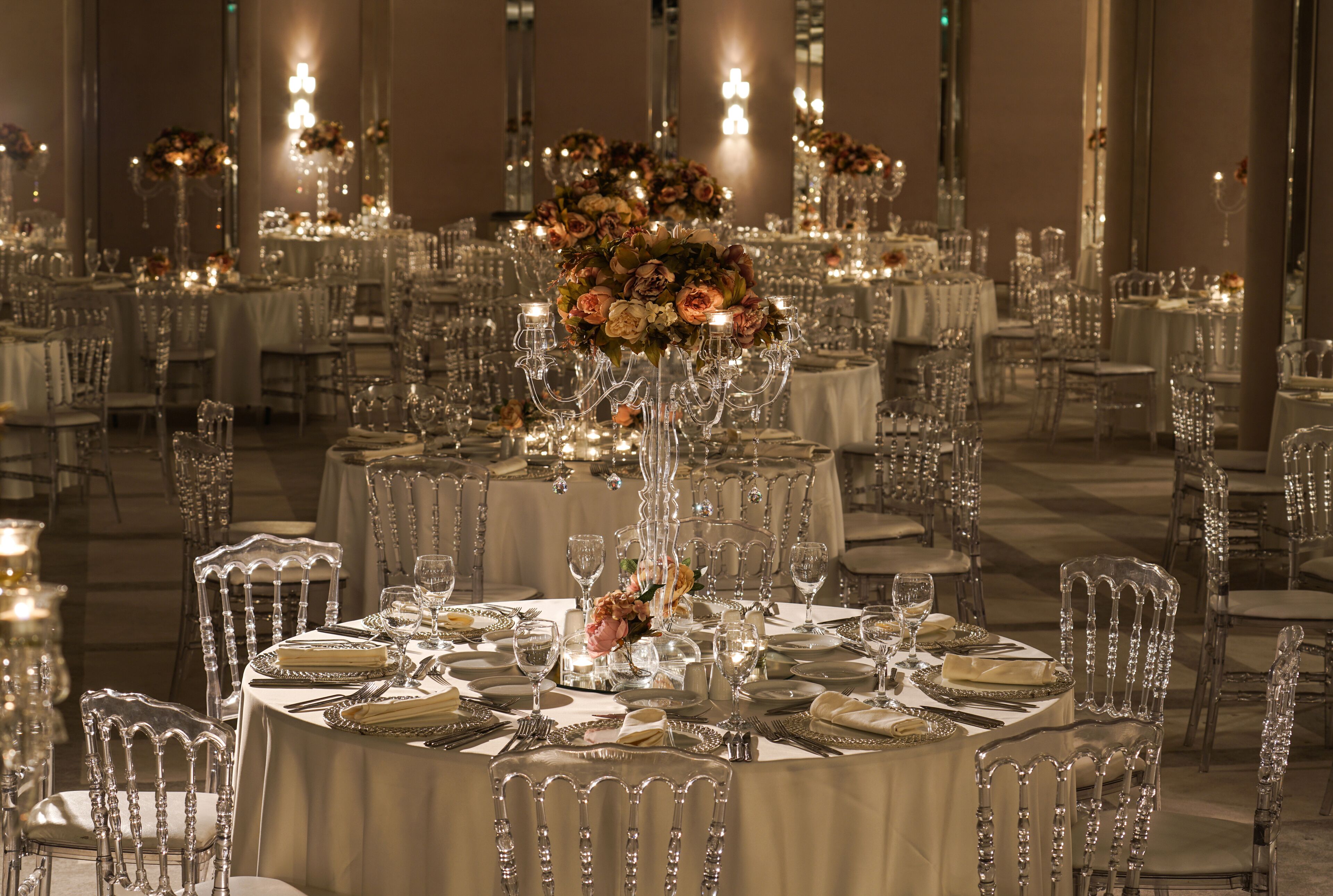 A banquet hall with round tables set for dining, each with a centerpiece and clear glassware.