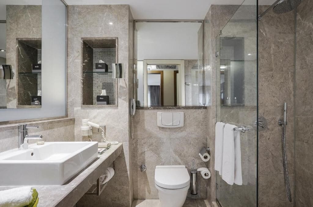 A modern bathroom with a large sink, toilet, and glass-enclosed shower.