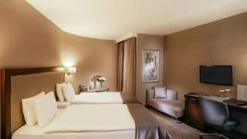 Habitación de hotel con dos camas, un escritorio, una silla, un televisor y un cuadro en la pared.