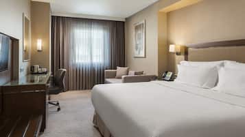 Una habitación de hotel con una cama grande, un escritorio con una silla, un televisor y un teléfono.