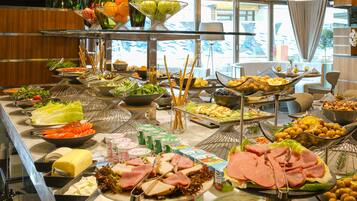 A buffet with various food items including meats, cheeses, fruits, and vegetables.