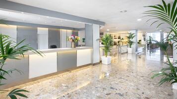 A modern reception area with a marble floor, potted plants, and a reception desk.