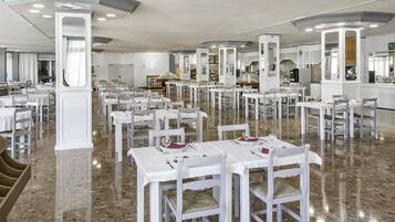 A spacious restaurant with white tables and chairs, marble flooring, and a modern interior design.