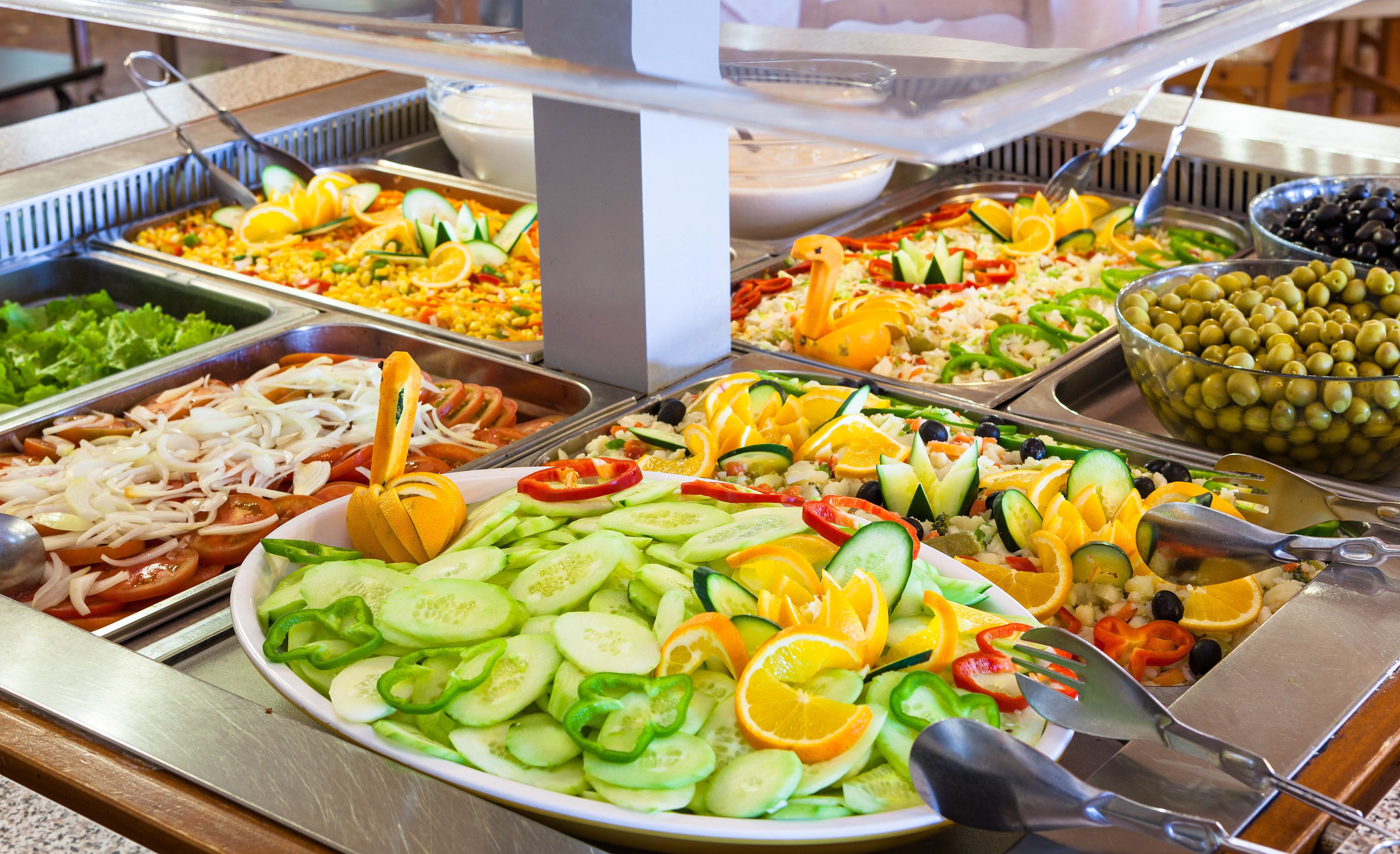 Un buffet con diverse opzioni tra cui insalate, frutta e verdura.