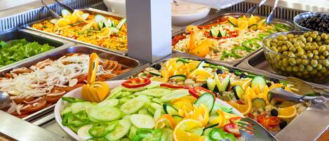 A buffet with various food options including salads, fruits, and vegetables.