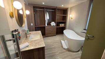Ein modernes Badezimmer mit freistehender Badewanne, einem Waschtisch und einem begehbaren Kleiderschrank.