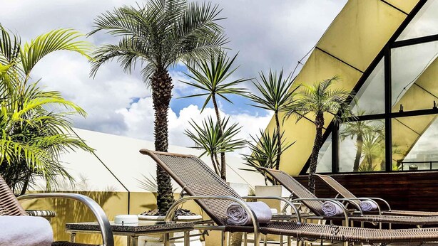 A rooftop lounge area with wicker lounge chairs, a pool table, and palm trees. - Grand Mercure Belem Do Para (Belém)