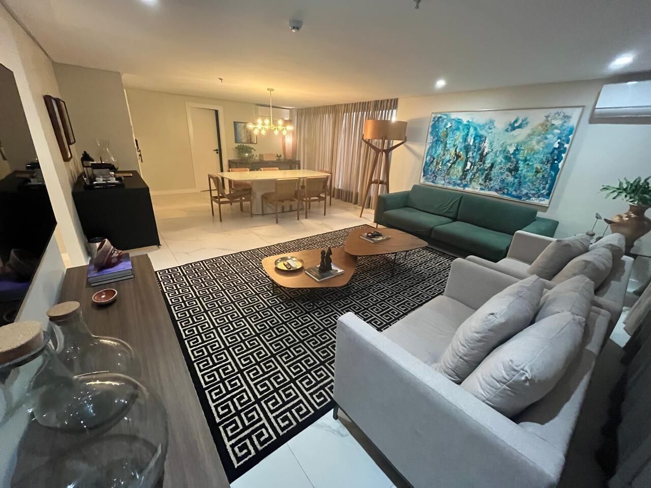 Una sala de estar con un sofá, una mesa de centro y un comedor con candelabro.