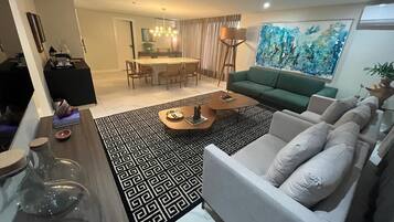 Una sala de estar con un sofá, una mesa de centro y un comedor con candelabro.