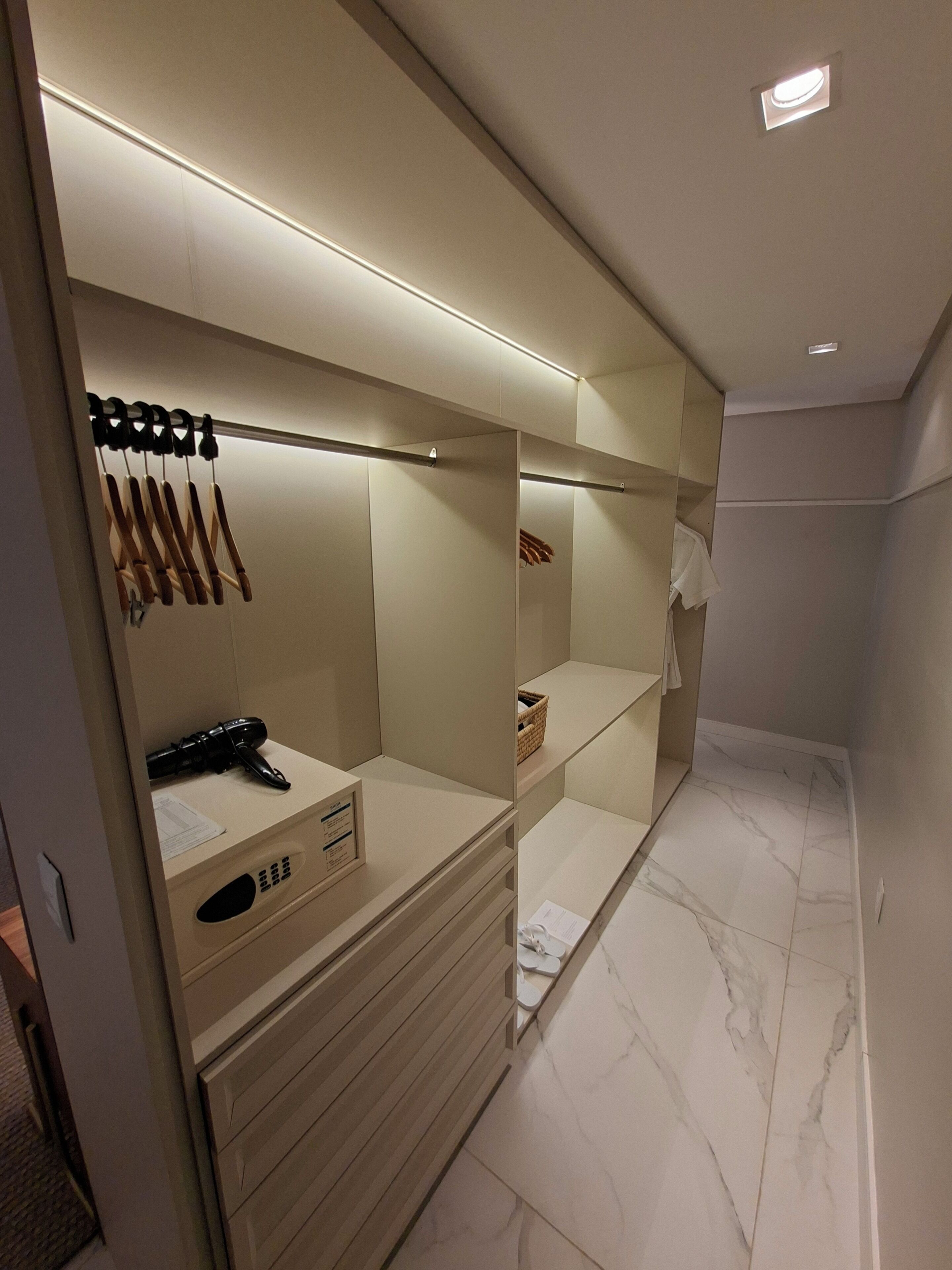 A modern closet with hanging space, a vanity with a mirror, and a small shelf.
