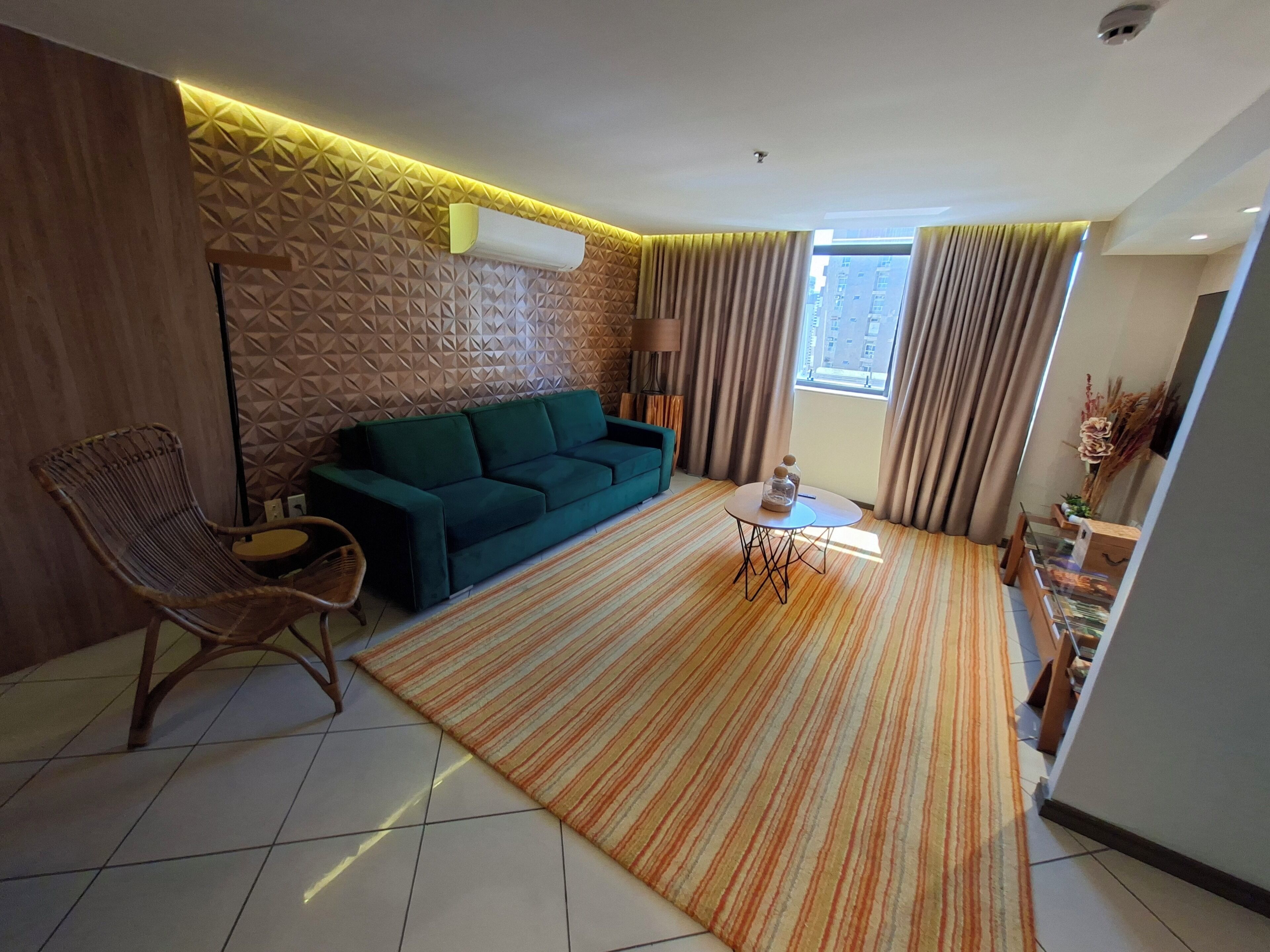 A modern living room with a sofa, a chair, a small table, and a patterned rug.