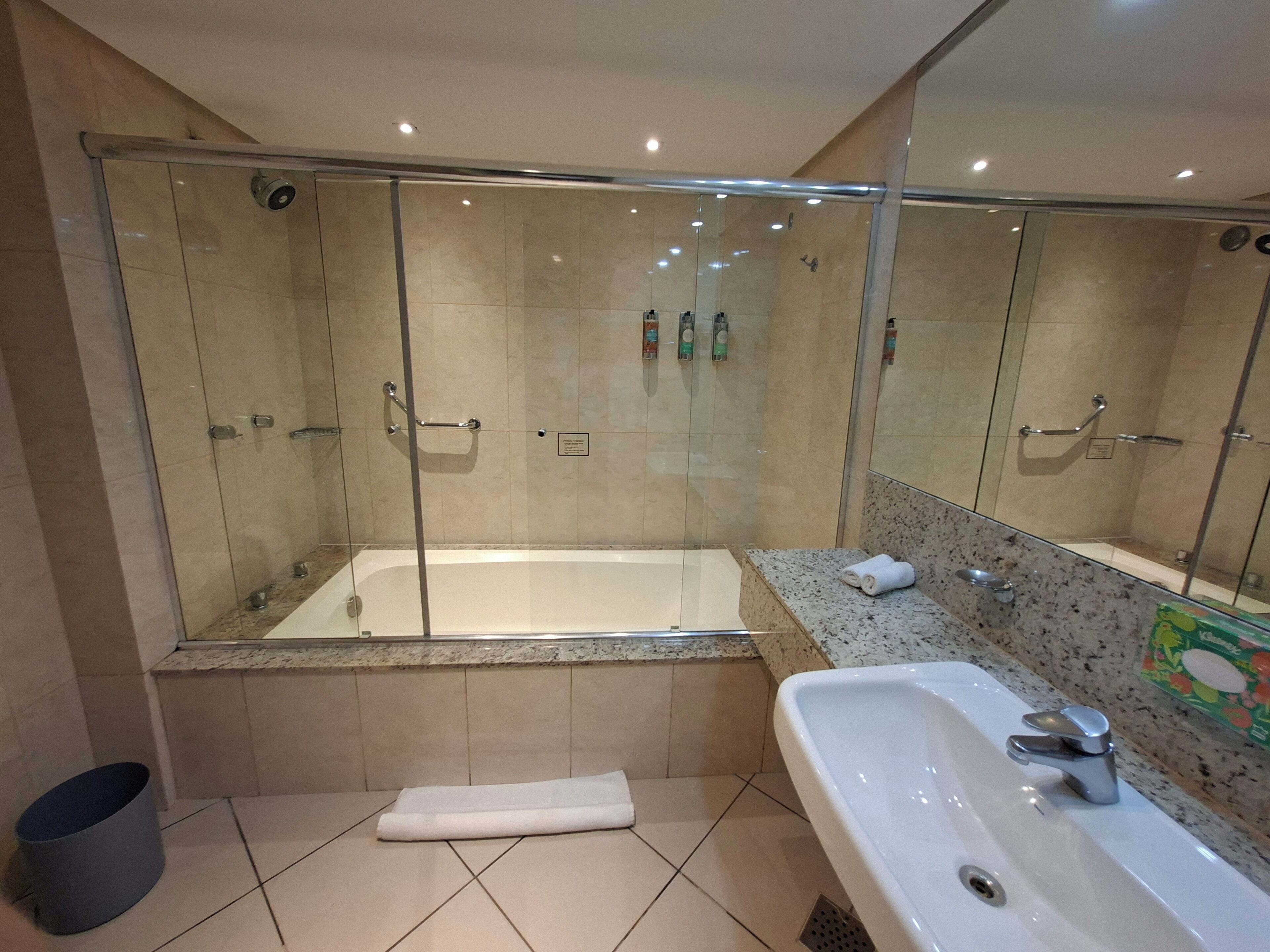 Une salle de bain moderne avec une douche à parois de verre, une baignoire sur pieds, un lavabo et un porte-serviettes.