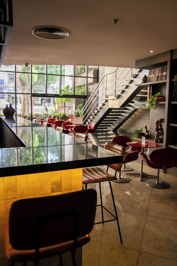 A modern interior with a bar area, seating, and a staircase leading to an upper level. - Grand Mercure Belem Do Para (Belém)