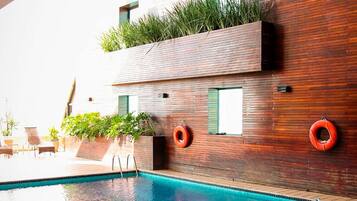 Una piscina al aire libre, sillones reclinables de piscina