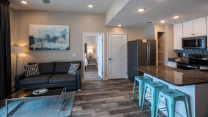 A modern kitchen with a central island, stainless steel appliances, and a dining area with a sofa and coffee table.