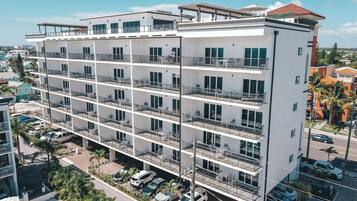 A multi-story building with balconies, a parking area, and a view of the surrounding neighborhood.