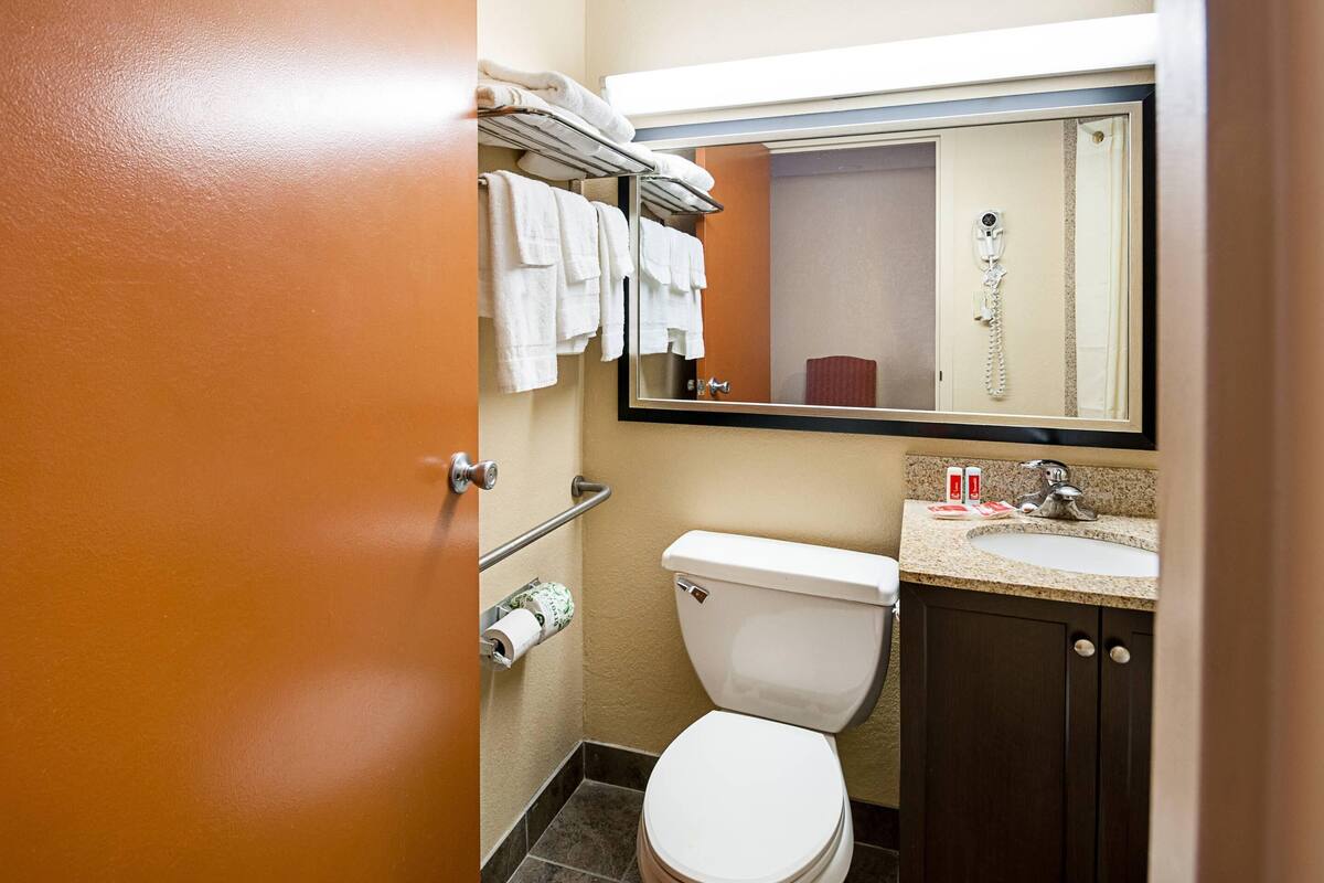 Un baño de hotel pequeño con inodoro, lavamanos y perchero para toallas.