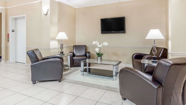 Een hotel lobby met lederen fauteuils, een glazen salontafel, een flatscreen televisie en een receptiebalie.