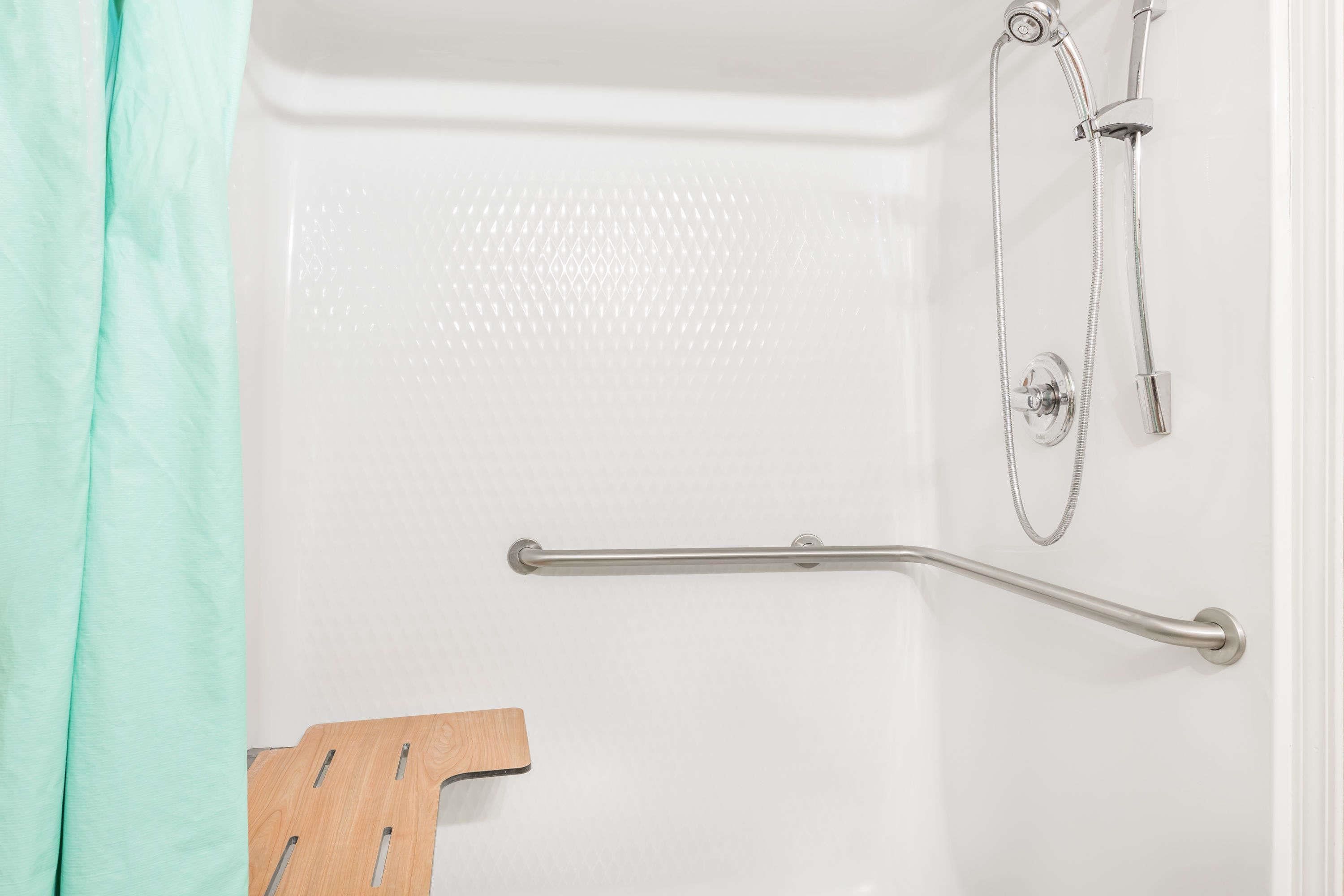 A shower area with a grab bar, a showerhead, and a handheld shower attachment.