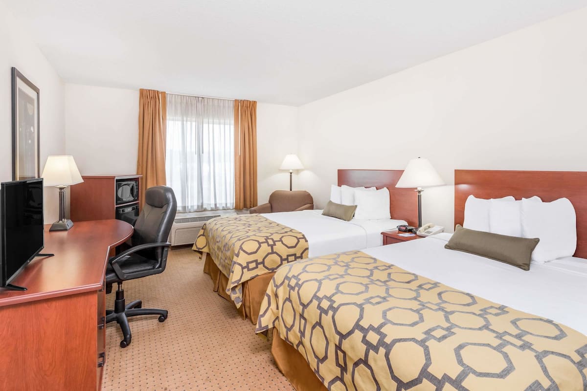 Habitació d'hotel amb dos llits, un escriptori amb un ordinador, una cadira i una televisió.