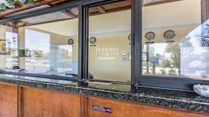 A reception area with a sign for Rodeway Inn & Suites, a clock, and a sign indicating wheelchair accessibility. - Rodeway Inn & Suites Canyon Lake-Menifee West (Menifee)