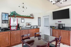 A kitchen with wooden cabinets, a coffee maker, a microwave, and a TV mounted on the wall.