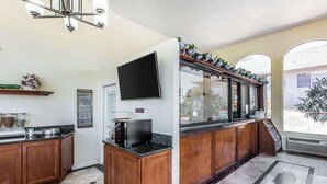 A modern kitchen with wooden cabinets, granite countertops, a built-in oven, and a large window with a view of the outdoors. - Rodeway Inn & Suites Canyon Lake-Menifee West (Menifee)