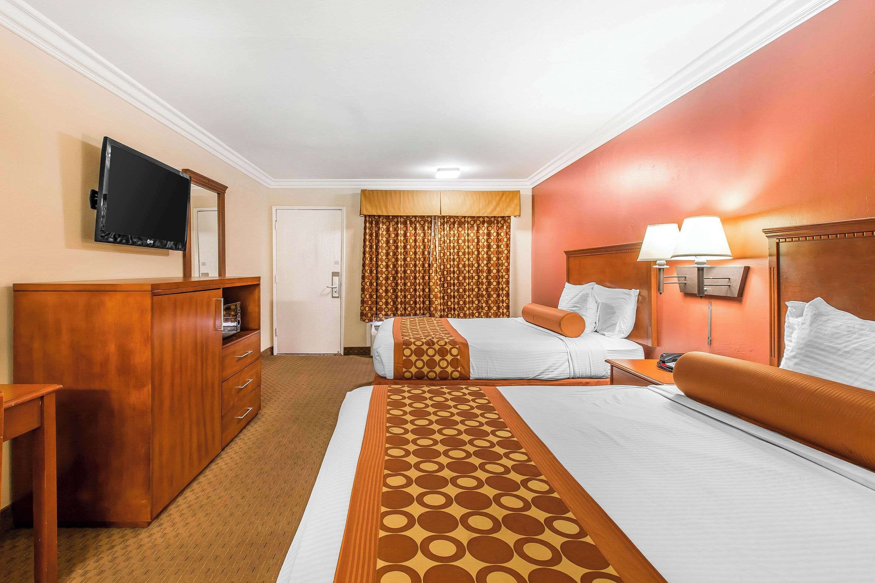 A hotel room with two beds, a TV, a desk, and a wardrobe.
