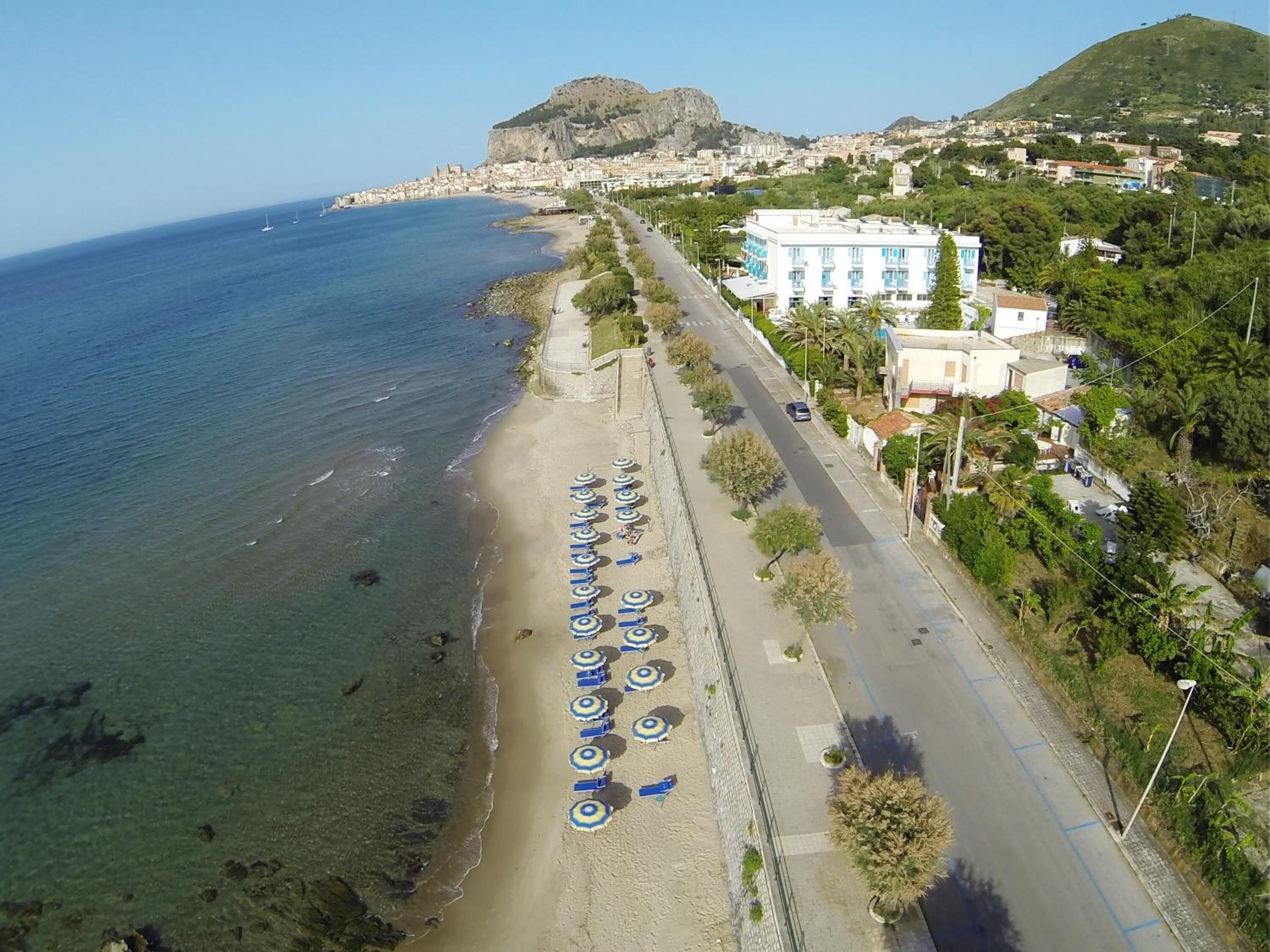 Una carretera costanera amb sombrerets de platja i un edifici amb façana blava.