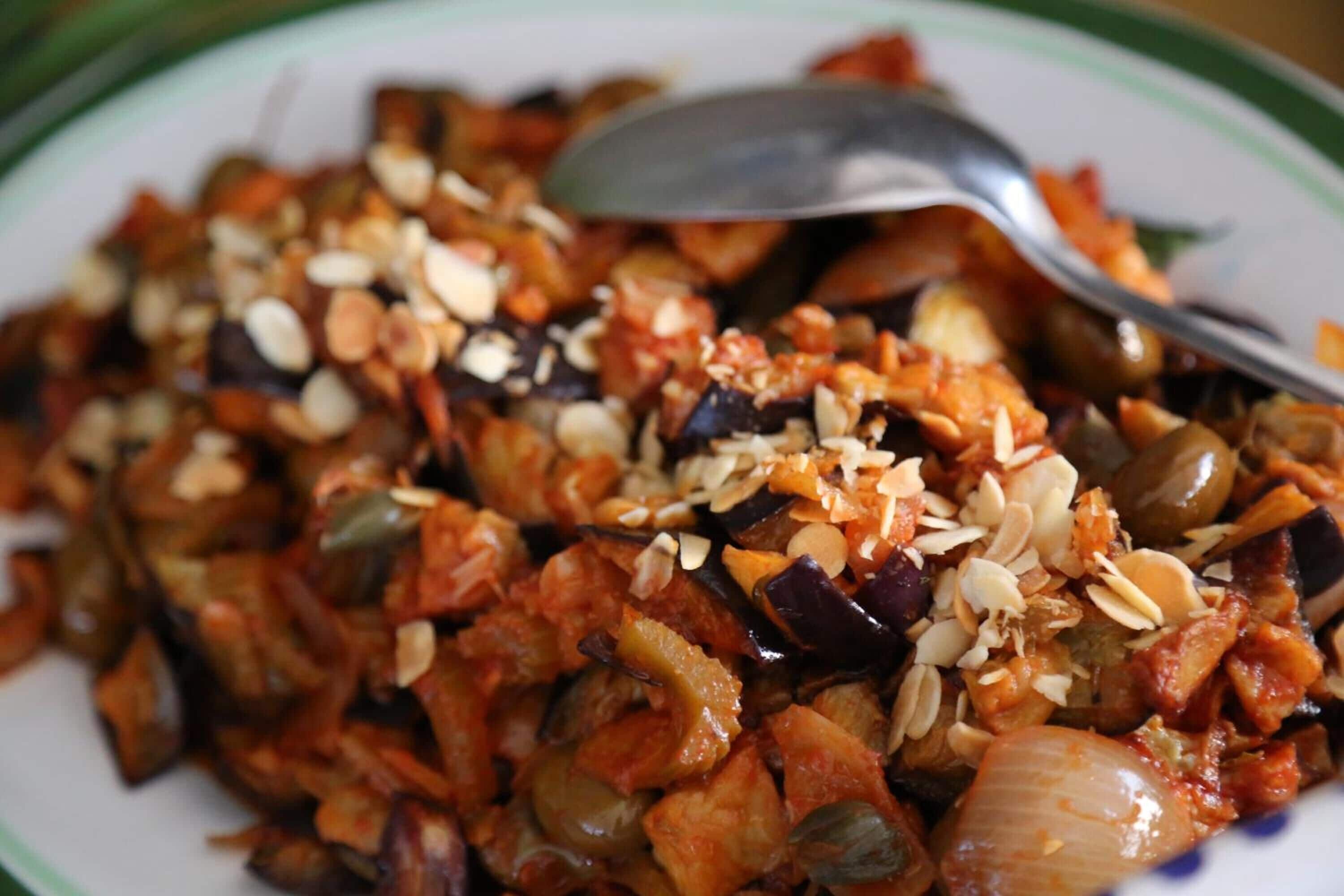 A plate of mixed vegetables with almonds on top.