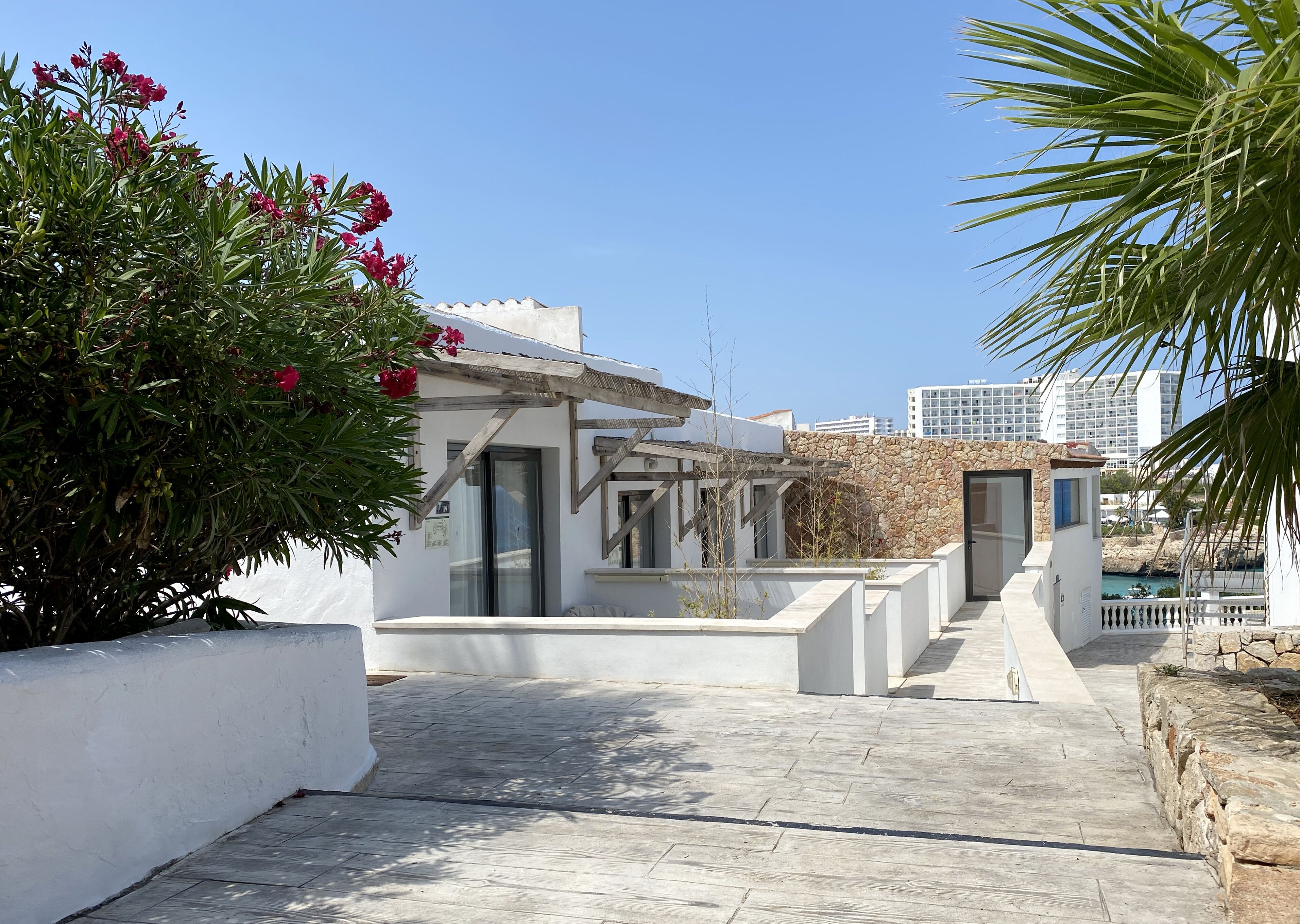 Een modern gebouw met een gevel van natuursteen, een overdekt terras en uitzicht op zee.