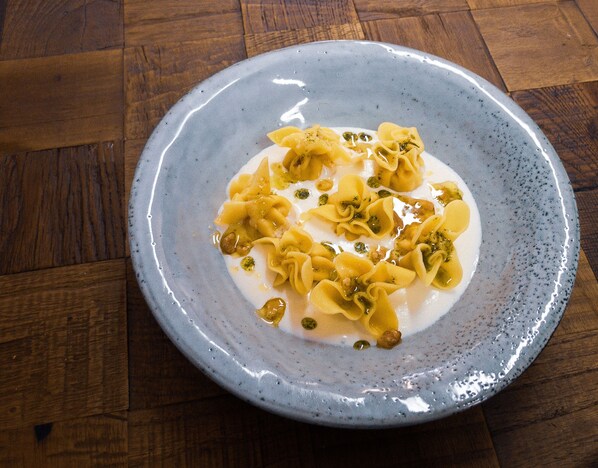 Un plato de pasta con salsa cremosa y alcaparras sobre un plato de cerámica con textura.