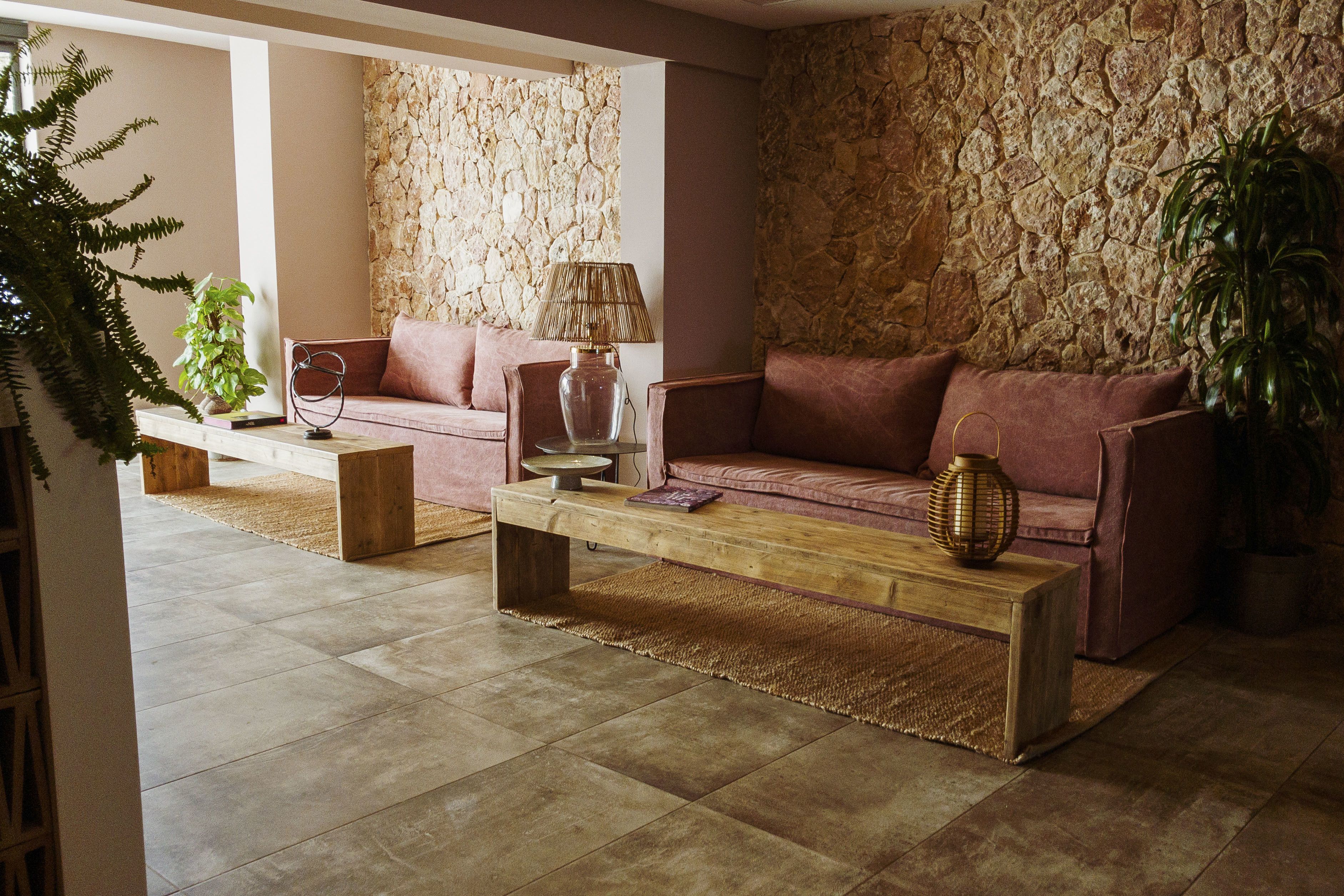 A living room with a stone wall, a sofa, a coffee table, and a lamp.