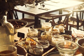 Une variété d’aliments sont présentés sur une table en bois, notamment des pots de sauces, des bols de noix et une carafe.