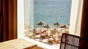 A room with a view of the sea, featuring a wooden table and chairs, and several straw umbrellas. - ICON Valparaiso - Adults Only (Manacor)