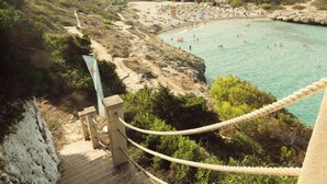 A coastal area with a beach, a rocky path, and a rope barrier. - ICON Valparaiso - Adults Only (Manacor)