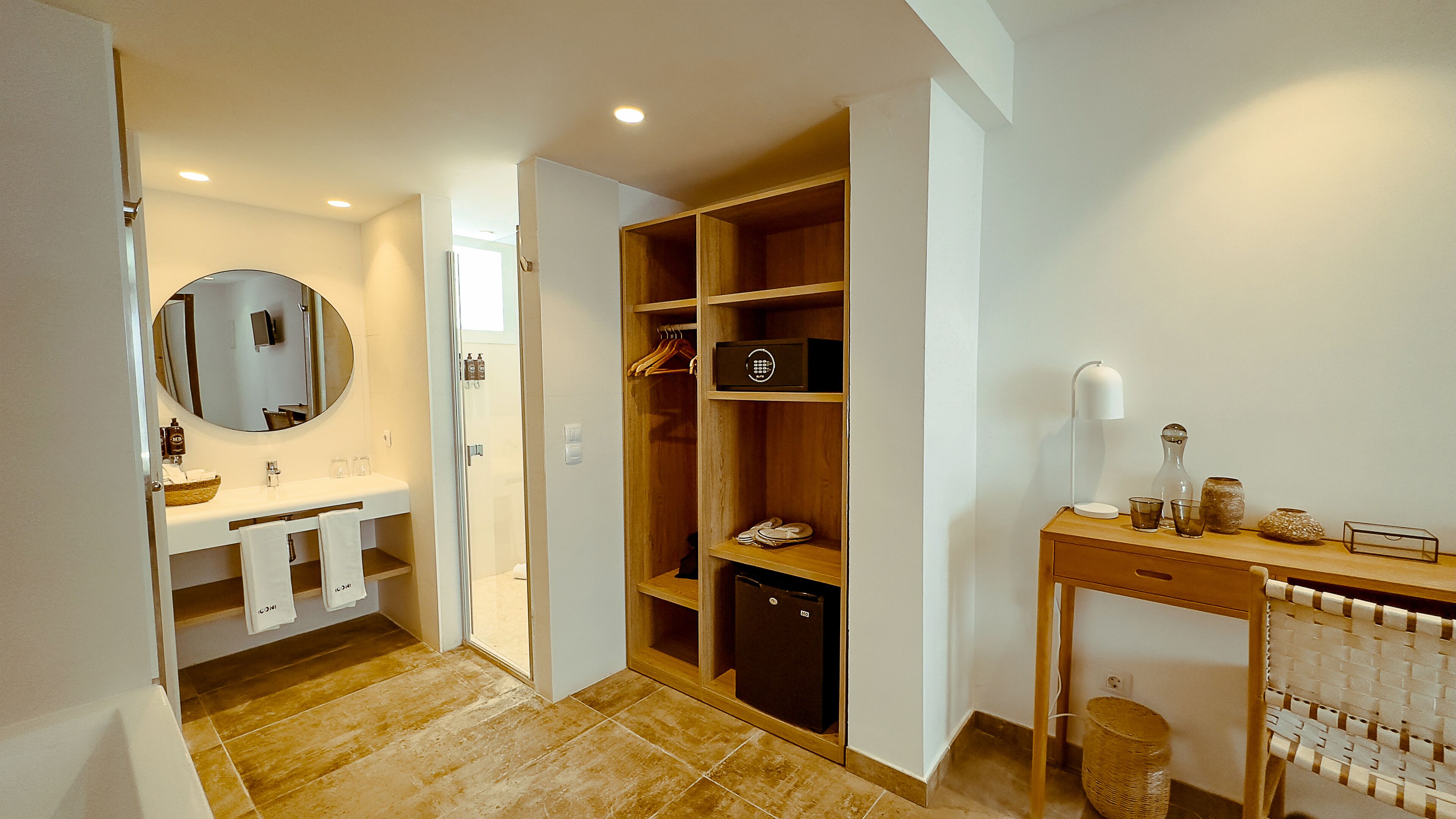 Un baño moderno con lavamanos, espejo y un vestidor con estantes y un refrigerador pequeño.