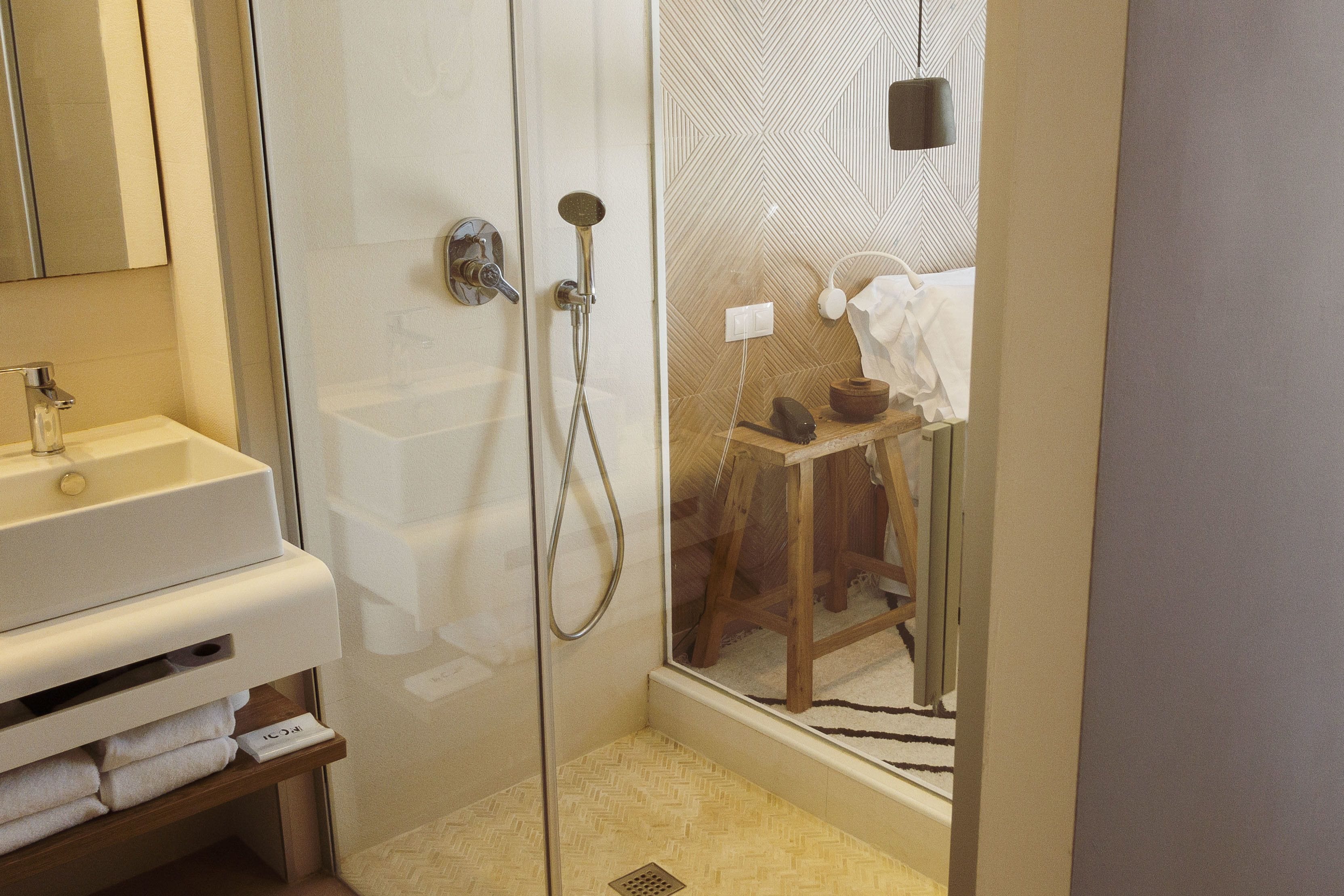 Un baño moderno con ducha de vidrio, lavamanos blanco y tocador de madera.
