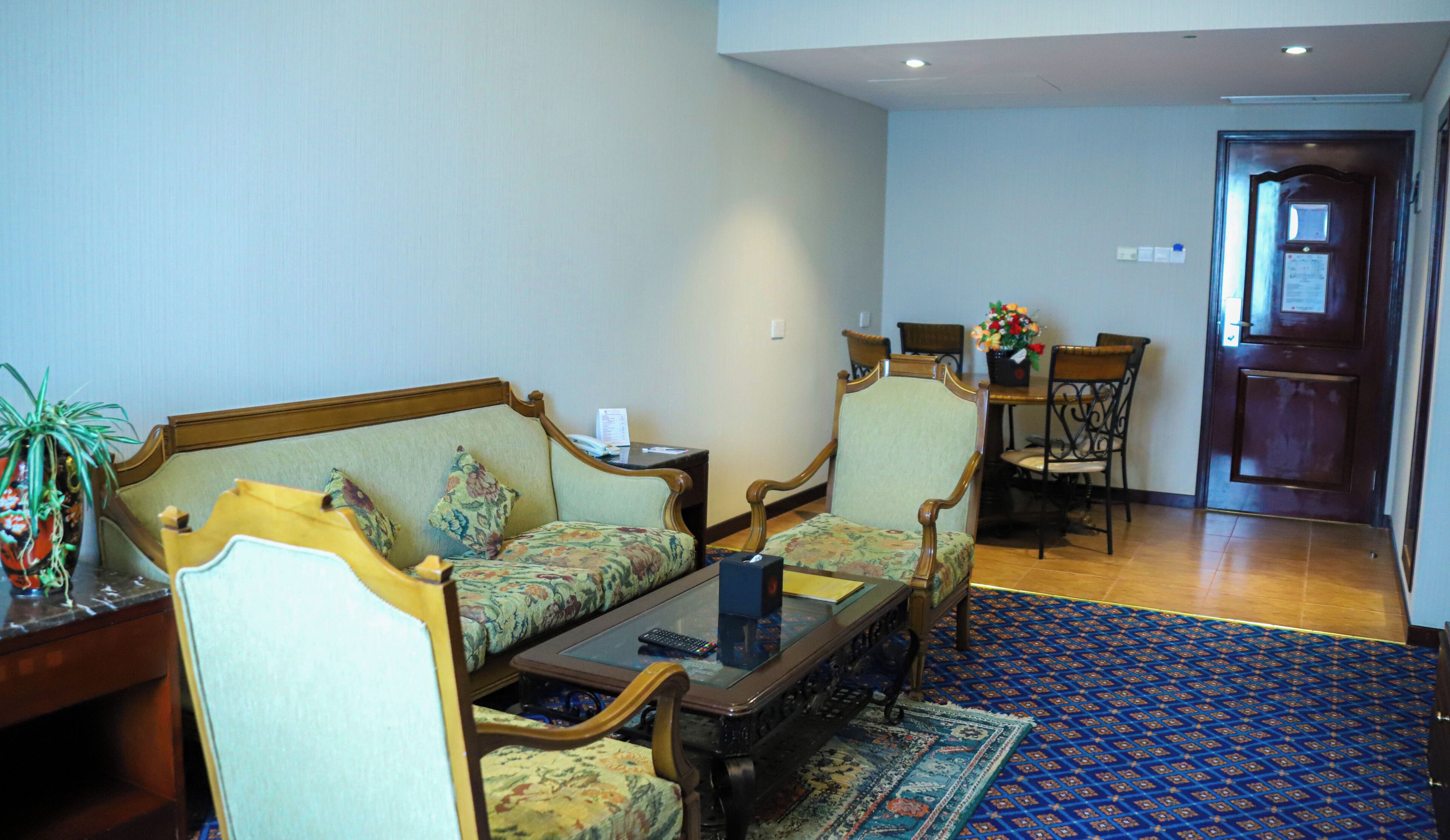 Ein Wohnzimmer mit einer Couch, Sesseln, einem Couchtisch und einem Essbereich mit Stühlen und einem Tisch.