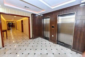 Elegant corridors lead to a modern elevator area with a patterned floor and dark wood paneling.