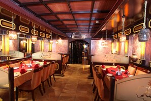 Ein Restaurant mit Holztischen und -stühlen, roten Tischdecken und hängenden Lampen.