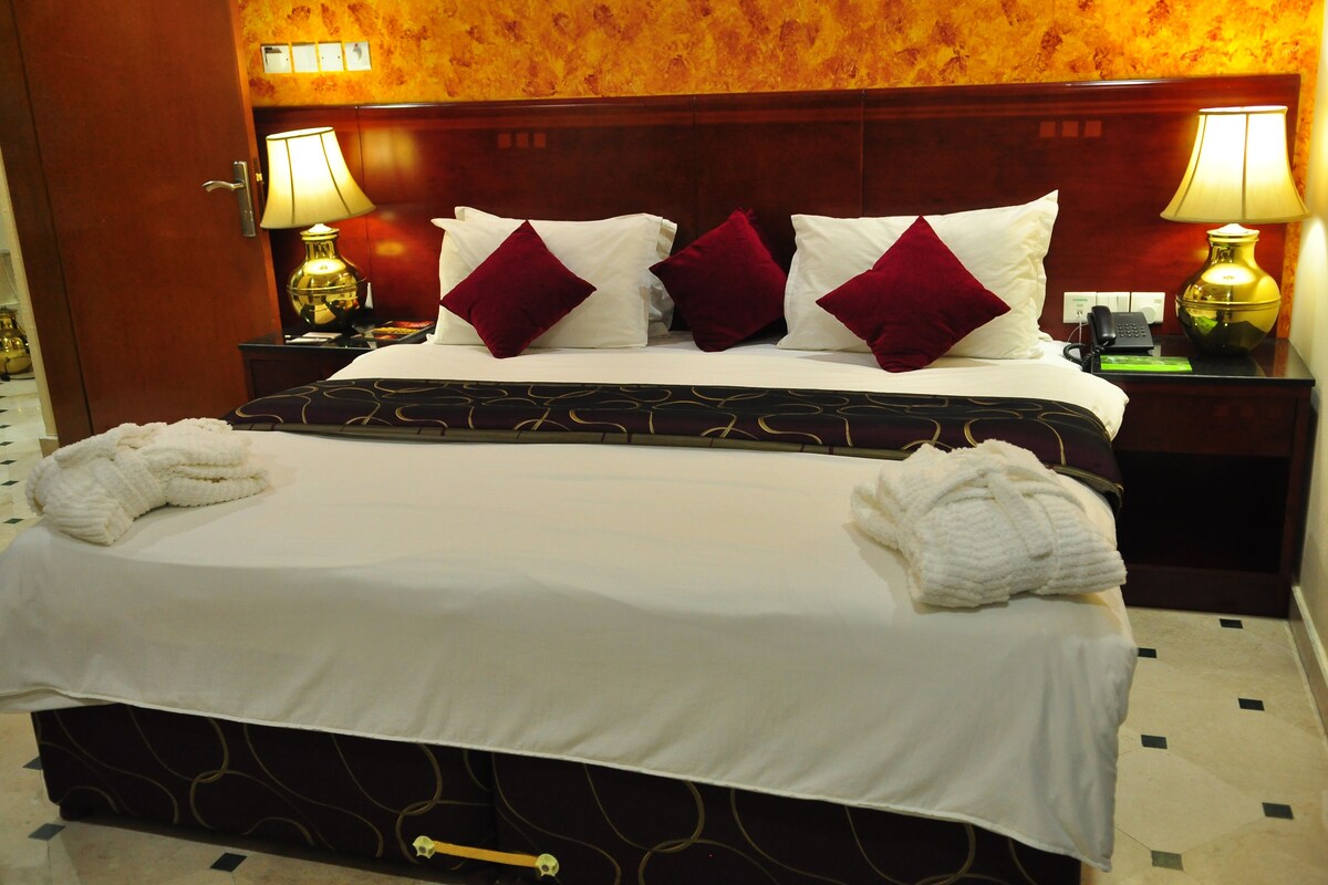 A hotel room with a large bed, two bedside tables, and two lamps.